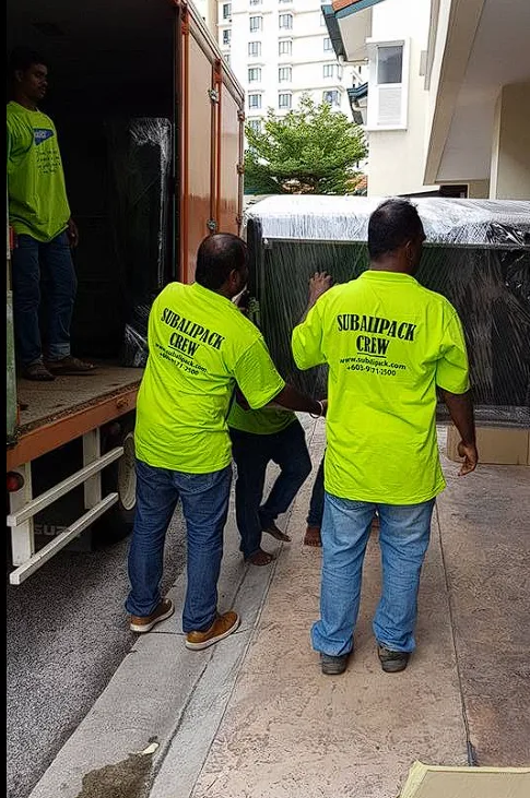 Crew loading a large shrink-wrapped item onto a lorry at an apartment block
