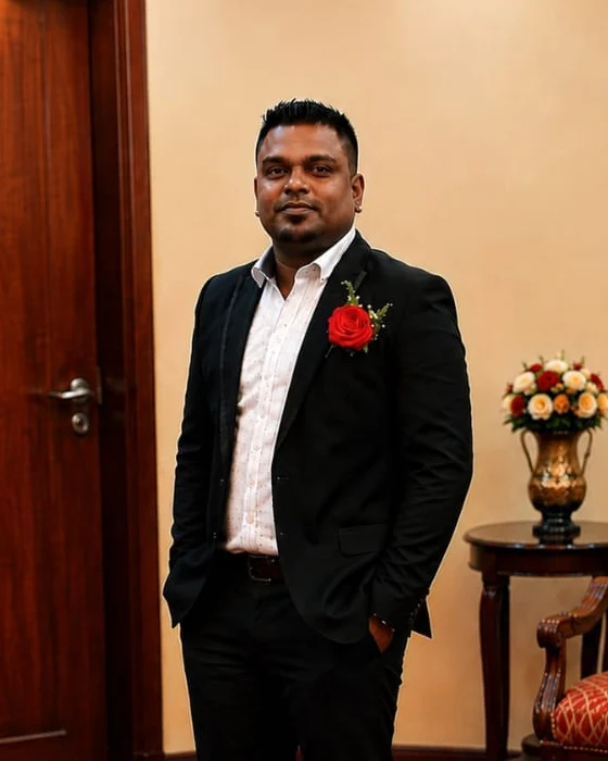 Mr. Xavier, Founder and CEO of Sky Line, standing in a dark suit with a red rose boutonniere