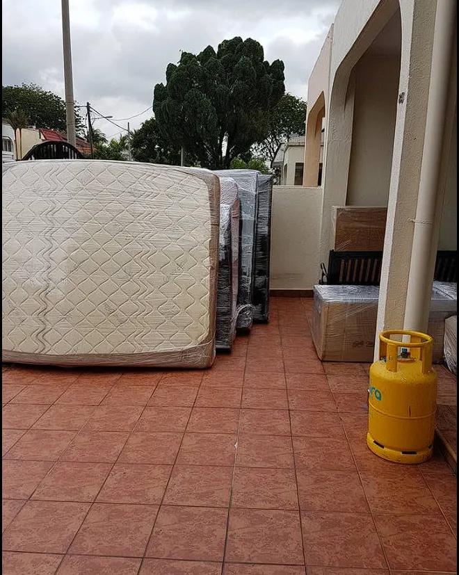 Mattresses and boxes wrapped in plastic on a house porch ready for loading