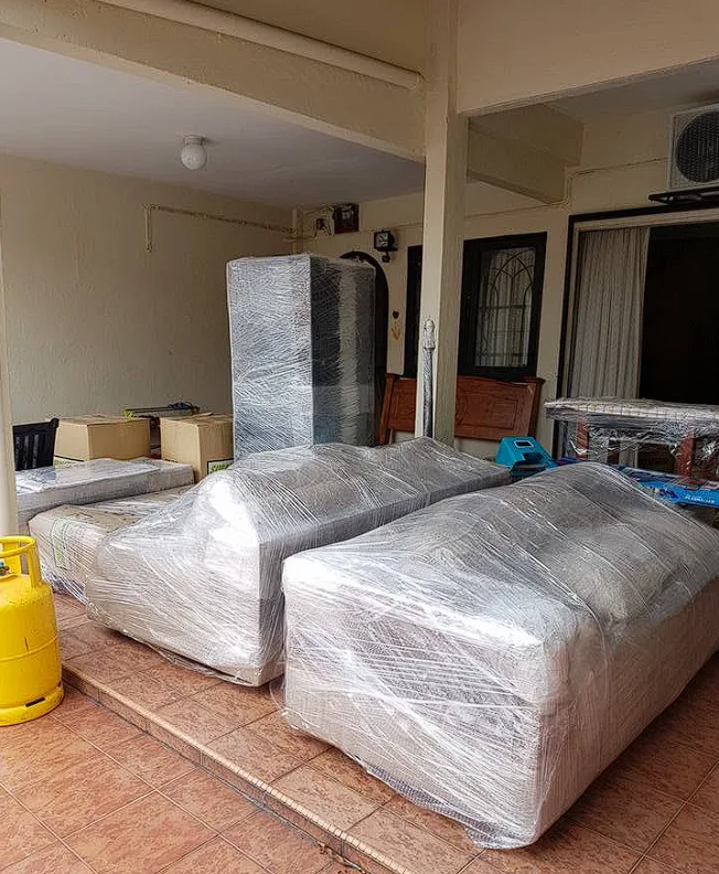 Three sofas shrink-wrapped and ready for the lorry outside a house