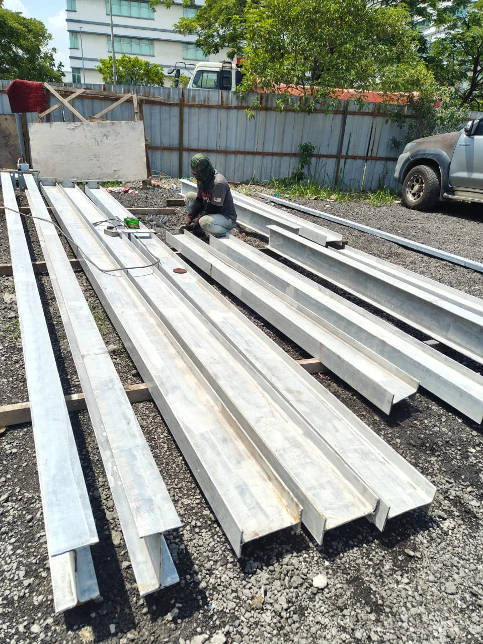 Worker preparing rows of steel beams in a fabrication yard