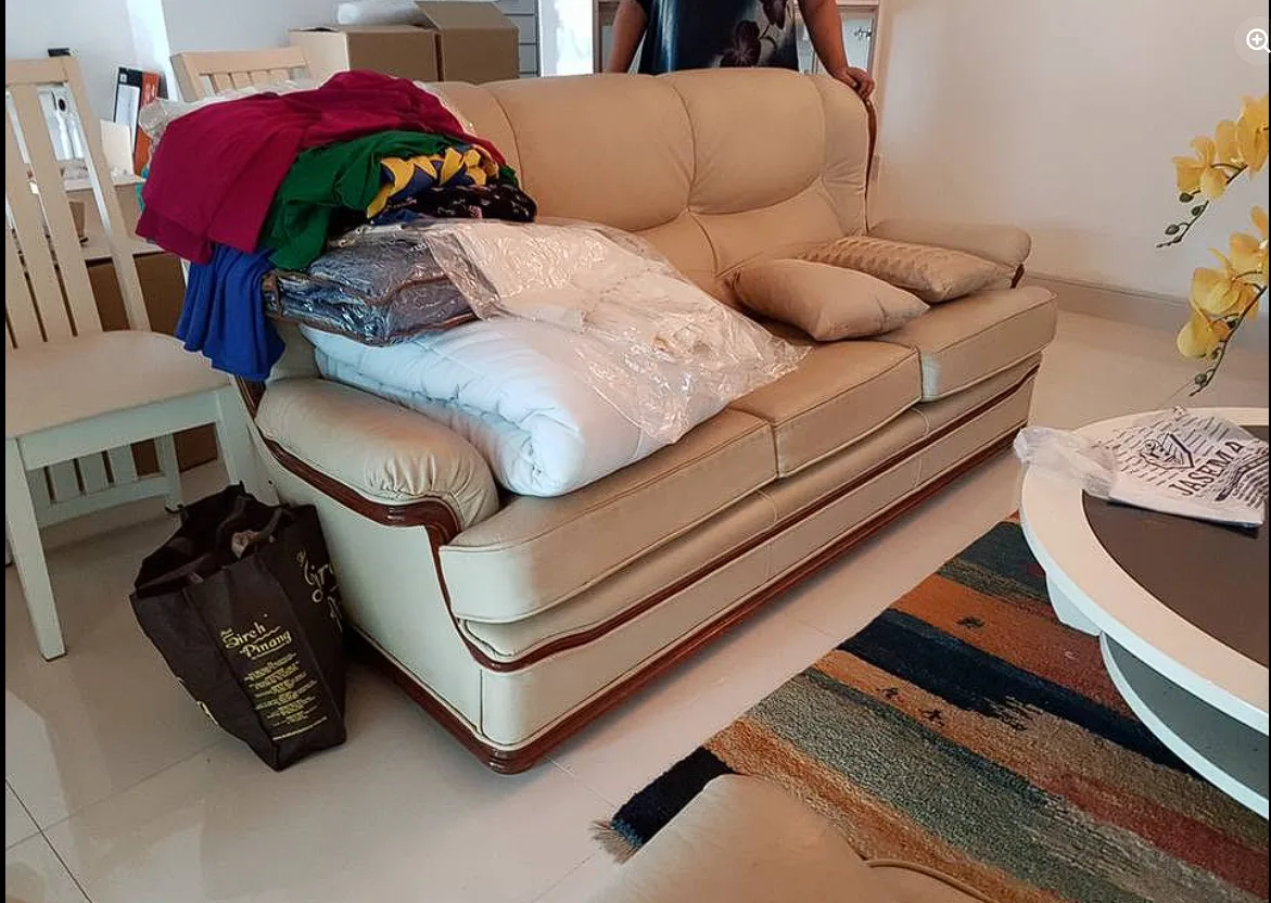 Sofa stacked with wrapped bedding and clothes during a house move