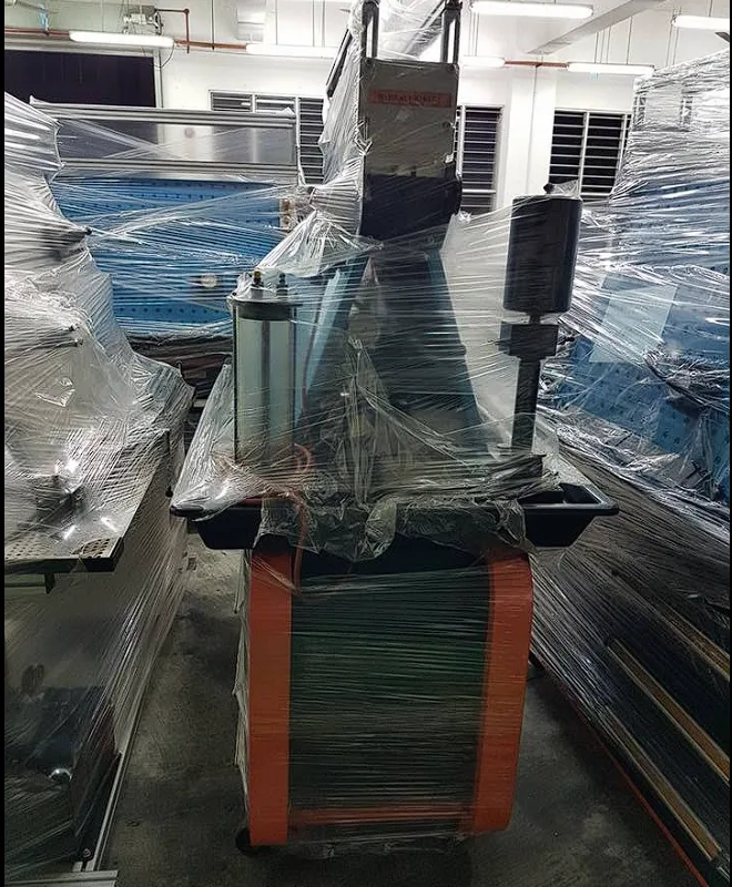 Hydraulic press machine shrink-wrapped among workshop benches
