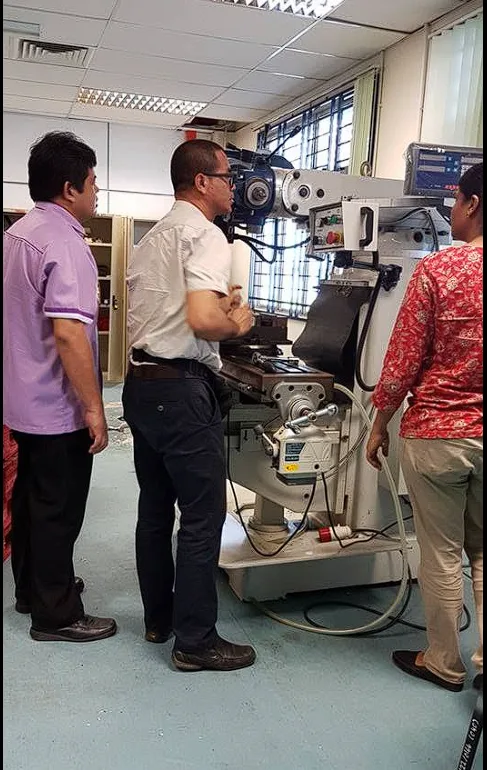 Team inspecting a milling machine after placement in a workshop