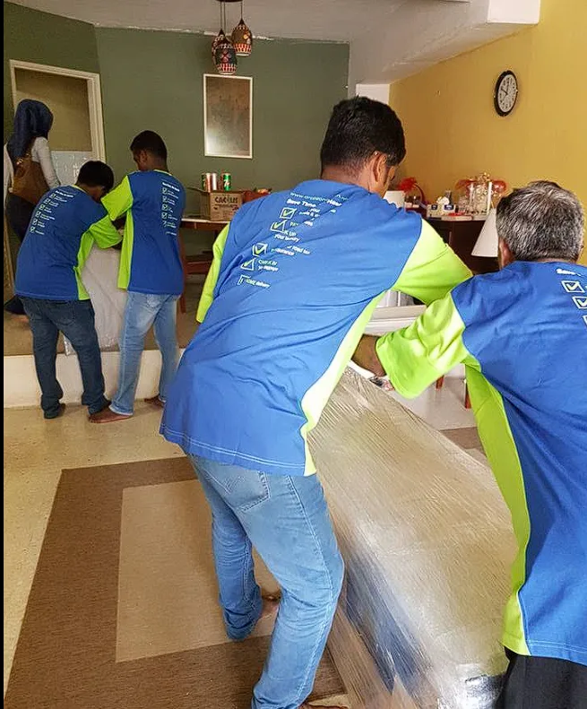 Crew carrying shrink-wrapped furniture out of a living room during a house move