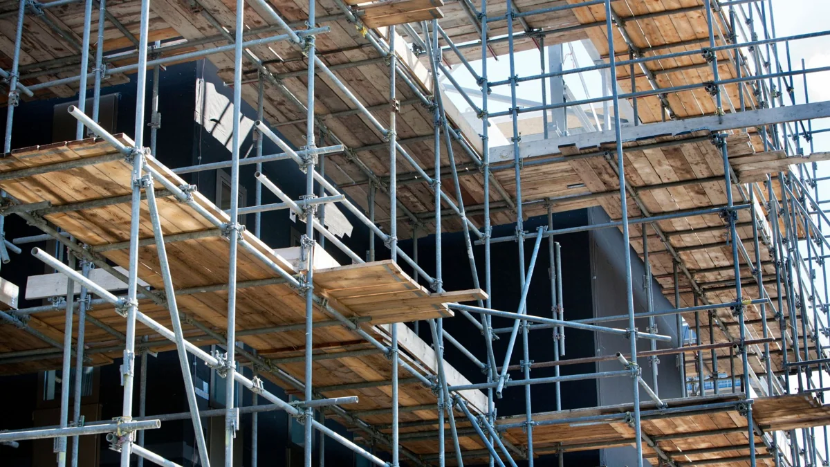 Steel scaffold poles and timber working platforms around a building facade