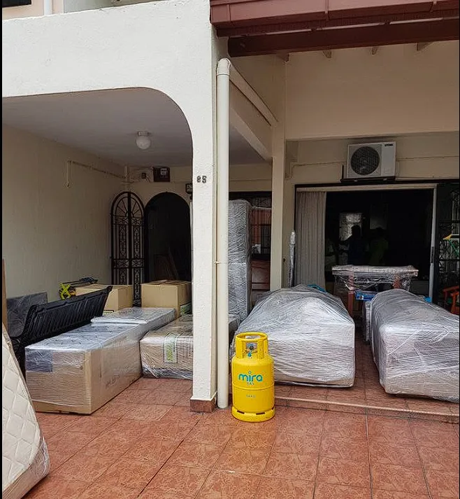 Sofas and boxes fully wrapped in plastic lined up on a house porch