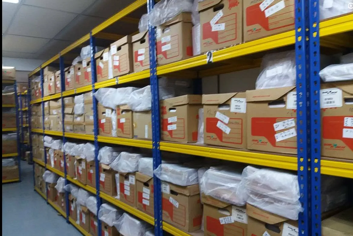 Rows of labelled archive boxes on yellow and blue storage racks